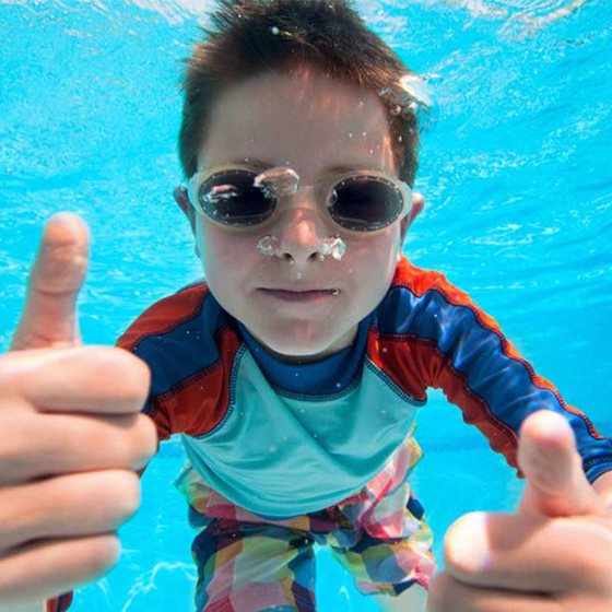 Jongen onderwater aan het zwemmen met zijn duikbril op